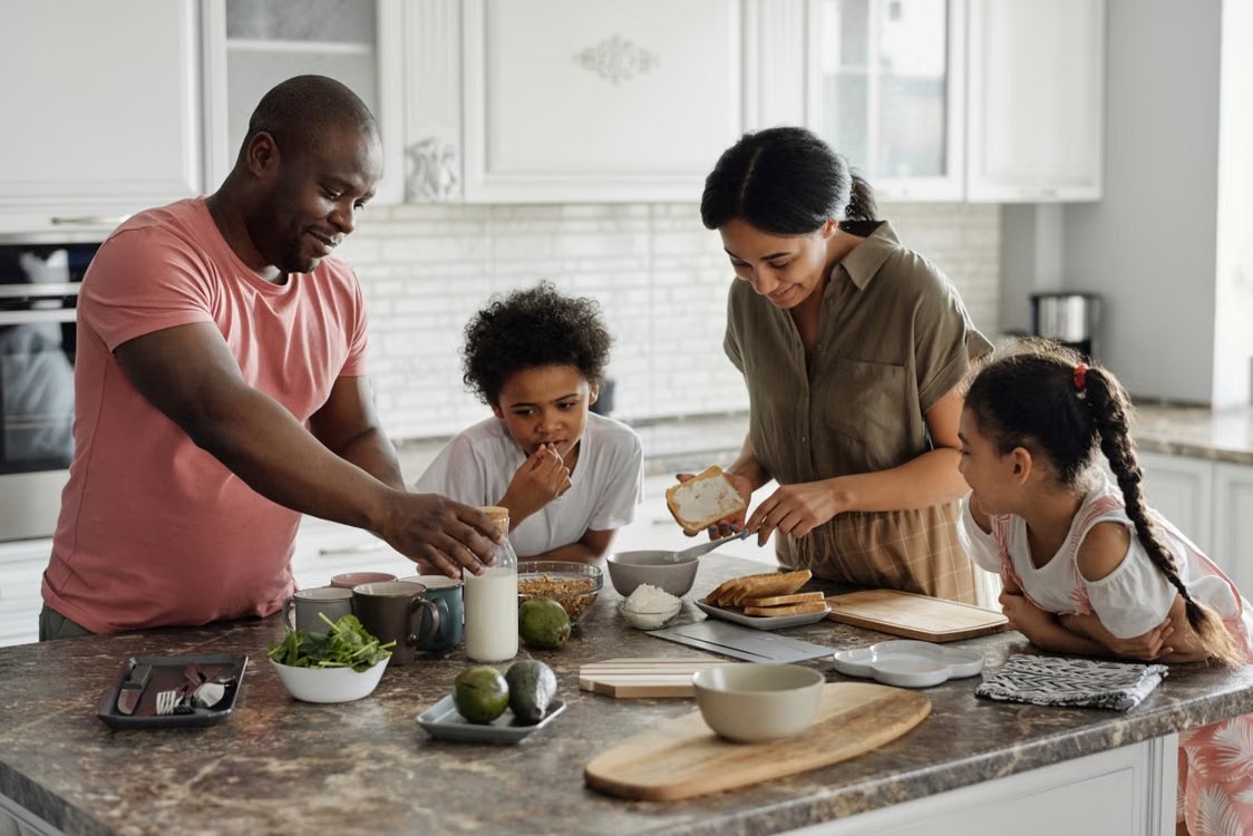 Family gathered together in a bright kitchen preparing a meal